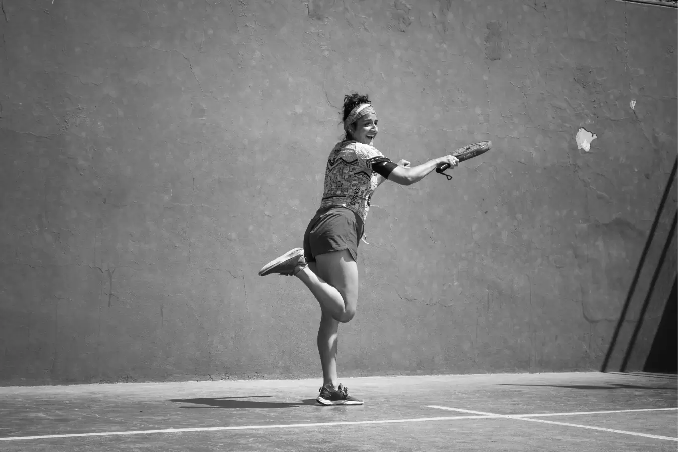 A padel player joyfully follows through after a shot, capturing the excitement and energy of the game.