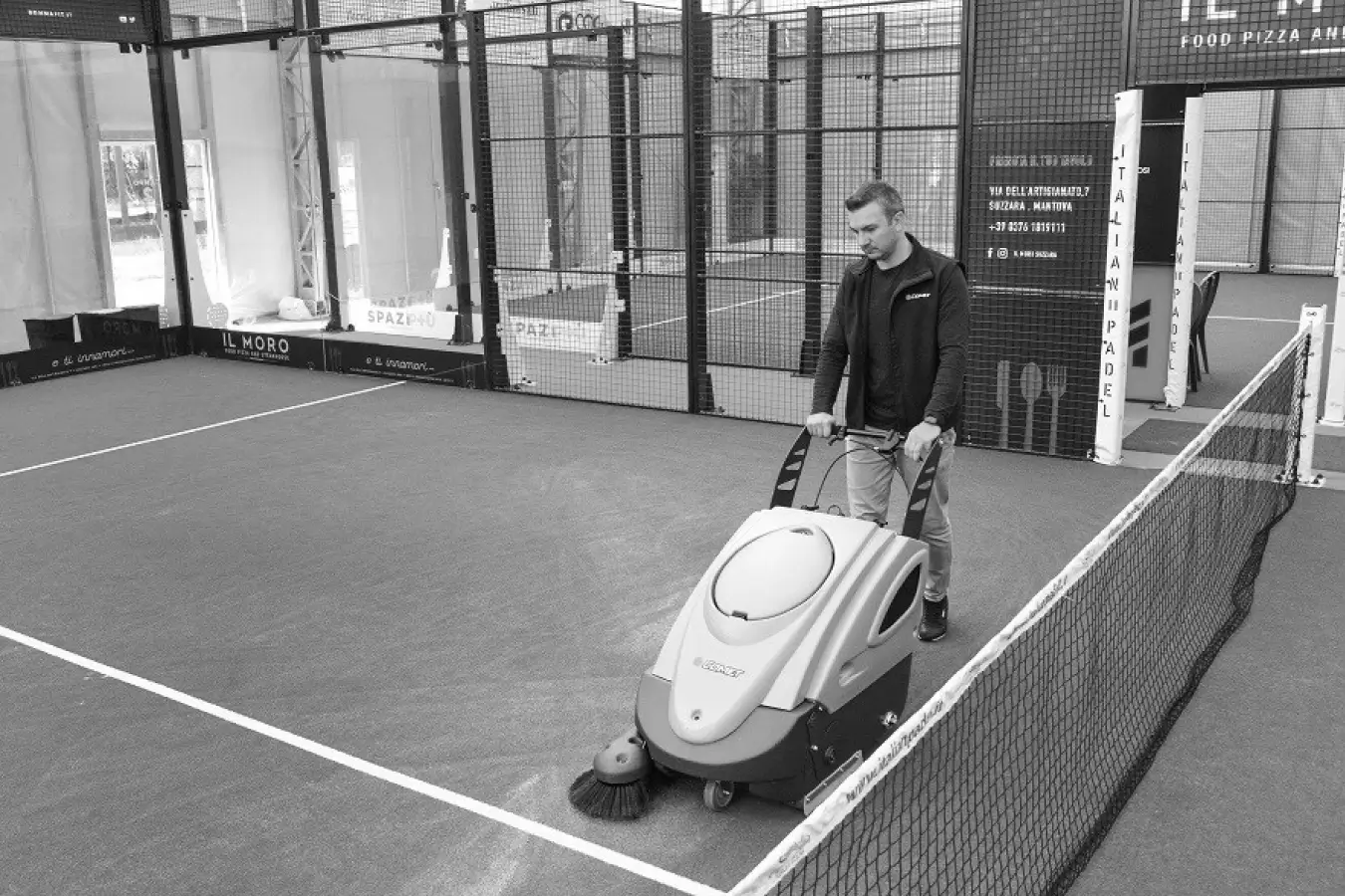 Man using a professional floor cleaning machine on a padel court to maintain surface quality and cleanliness.